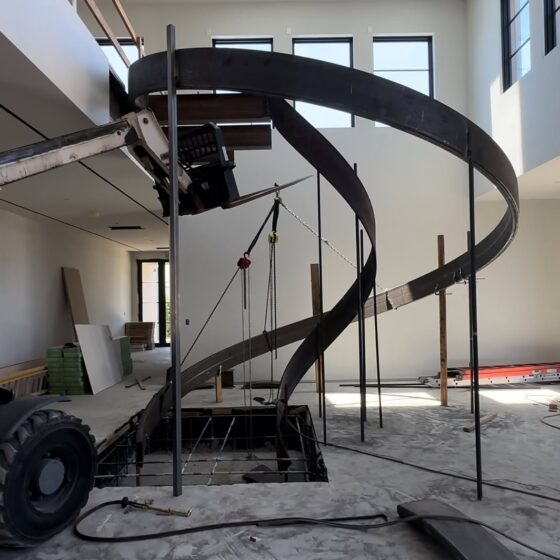 Steel spiral staircase frame being lifted and installed on site