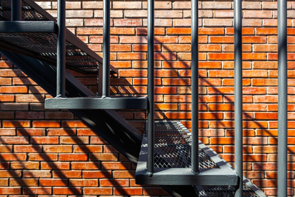 Steel staircase with anti-slip mesh treads against brick wall
