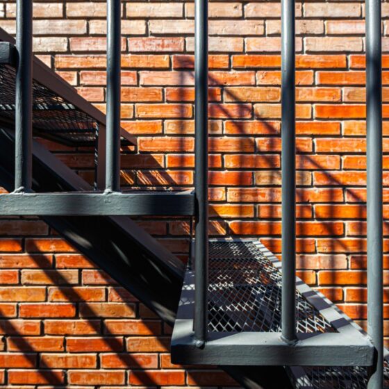 Steel staircase with anti-slip mesh treads against brick wall