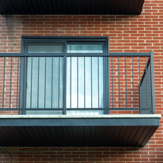 Small steel balcony with simple vertical bars on red brick building