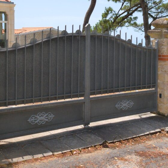 Classic grey metal driveway gate with stone pillars and decorative detail