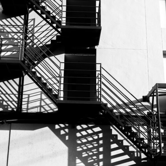 Steel external fire escape staircase with shadow on building wall