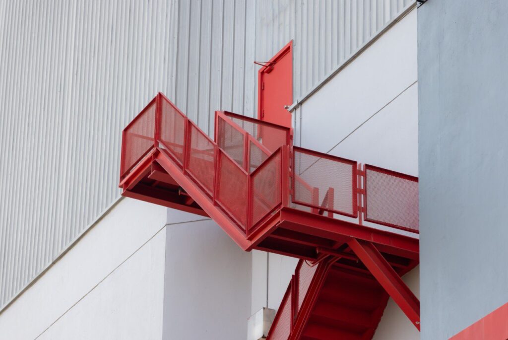 Red steel fire escape staircase with emergency exit door