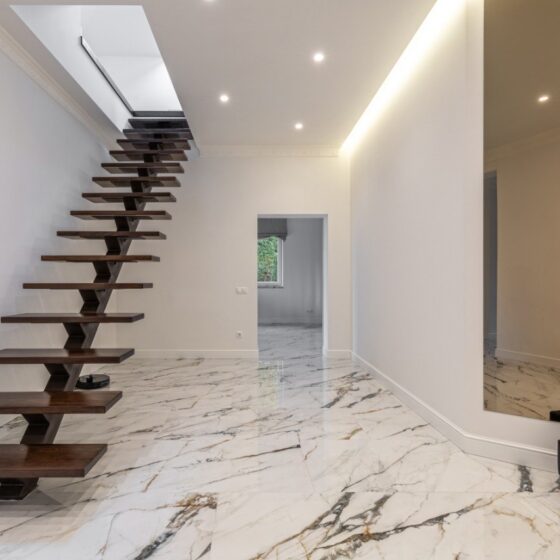 Dark timber floating staircase ideal for contemporary homes with modern marble flooring