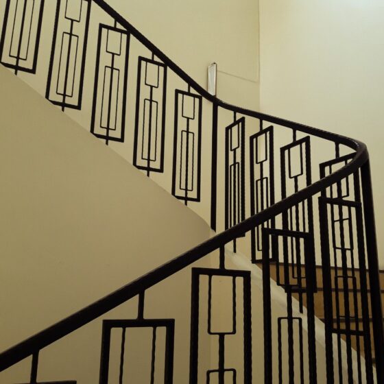Interior staircase with black steel balustrade featuring geometric pattern