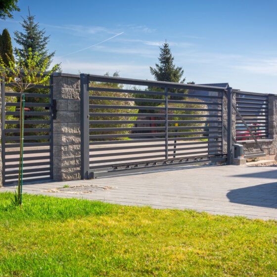 Modern sliding gate with horizontal steel bars and stone pillars