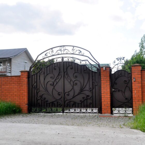 Decorative ornamental iron gate with scrollwork set in red brick wall