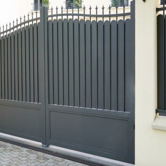 Tall black steel driveway gate with vertical panel design for security