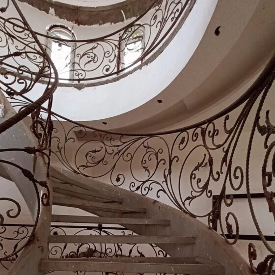 Ornate wrought-iron balustrade on curved staircase, scrollwork detail